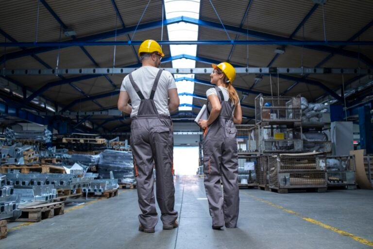 Dos trabajadores con casco recorren una nave industrial