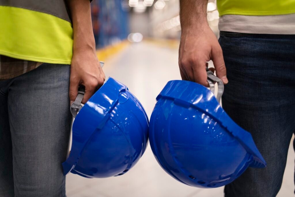 Dos trabajadores industriales sostienen sus cascos de protección
